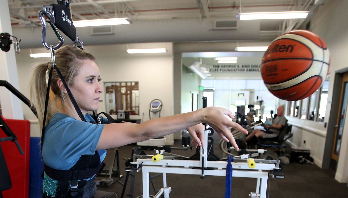 Kendal Levine, who was hit by a car while on a mission in Australia, passes a basketball as she works with physical therapist Marissa Moran at Neuroworx in Sandy on Thursday, April 25, 2019.
