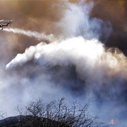 A firefighting sky crane helicopter dumps a load of water on new wildfire which started late Monday afternoon next to Magic Mountain in Santa Clarita, Calif., north of Los Angeles.