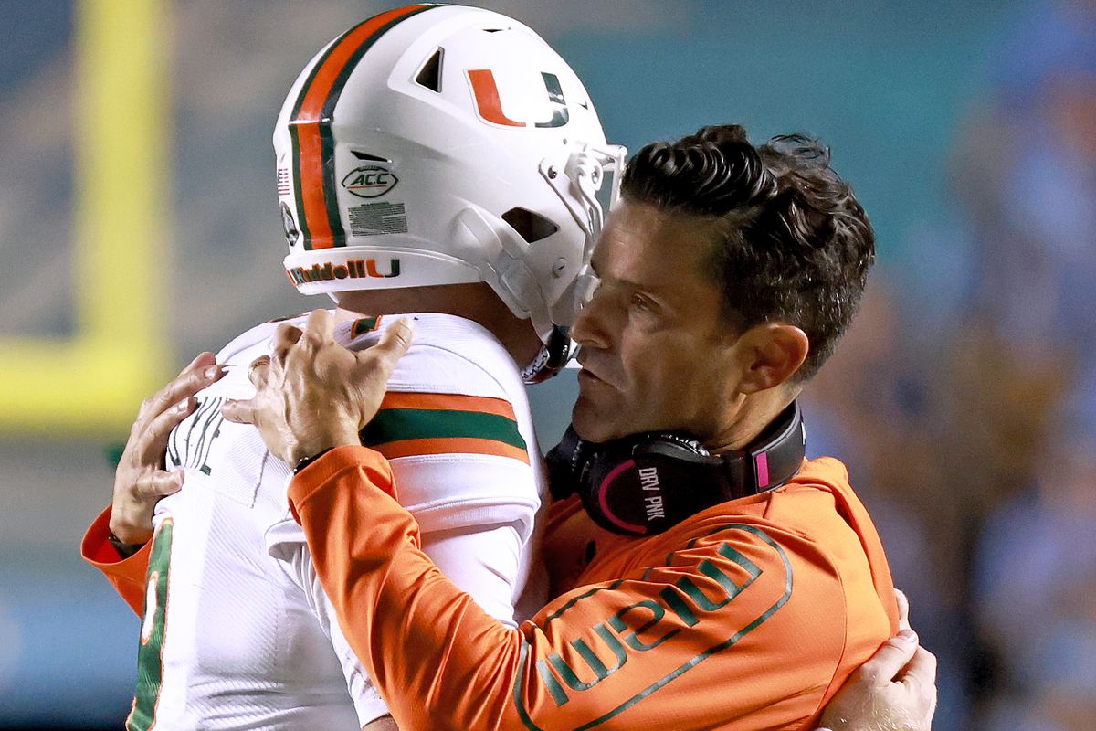 Head coach Manny Diaz embraces Tyler Van Dyke of the Miami Hurricanes after Van Dyke’s interception late in the fourth quarter of their game against the North Carolina Tar Heels at Kenan Memorial Stadium on October 16, 2021 in Chapel Hill, North Carolina. North Carolina won 45-42.