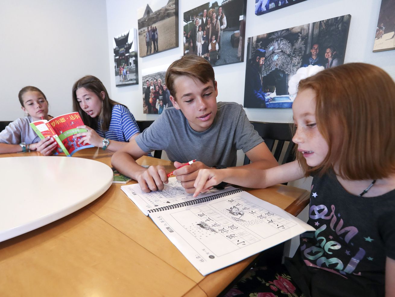 Katrina Hilton, left, listens as her sister, Maria, reads from a book written in Chinese as their brother, Joseph, helps sister, Rebekah, with her Chinese in their home in Orem on Thursday, June 25, 2020. The siblings all attend dual language immersion schools.