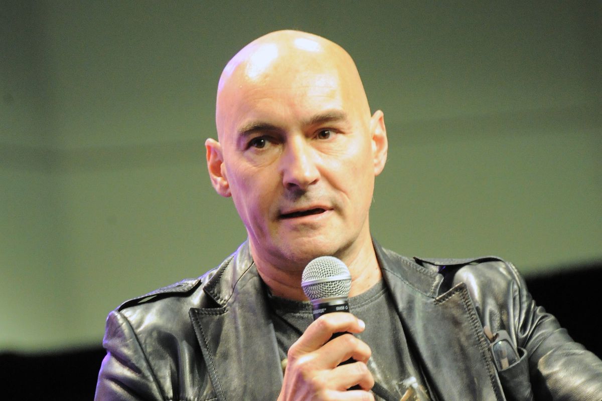 Grant Morrison speaks on stage at a comics convention