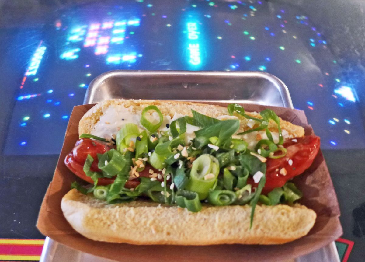 A hot dog is topped with scallions on a cosmic background.