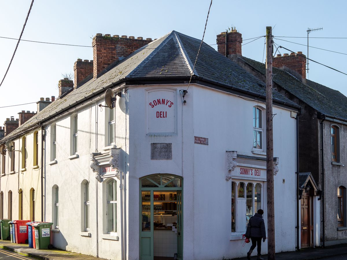 The entrance to Sonny’s Deli in a traditional Georgian style block of buildings with simple white facade and steeped roof, with the name of the restaurant in red lettering above the door