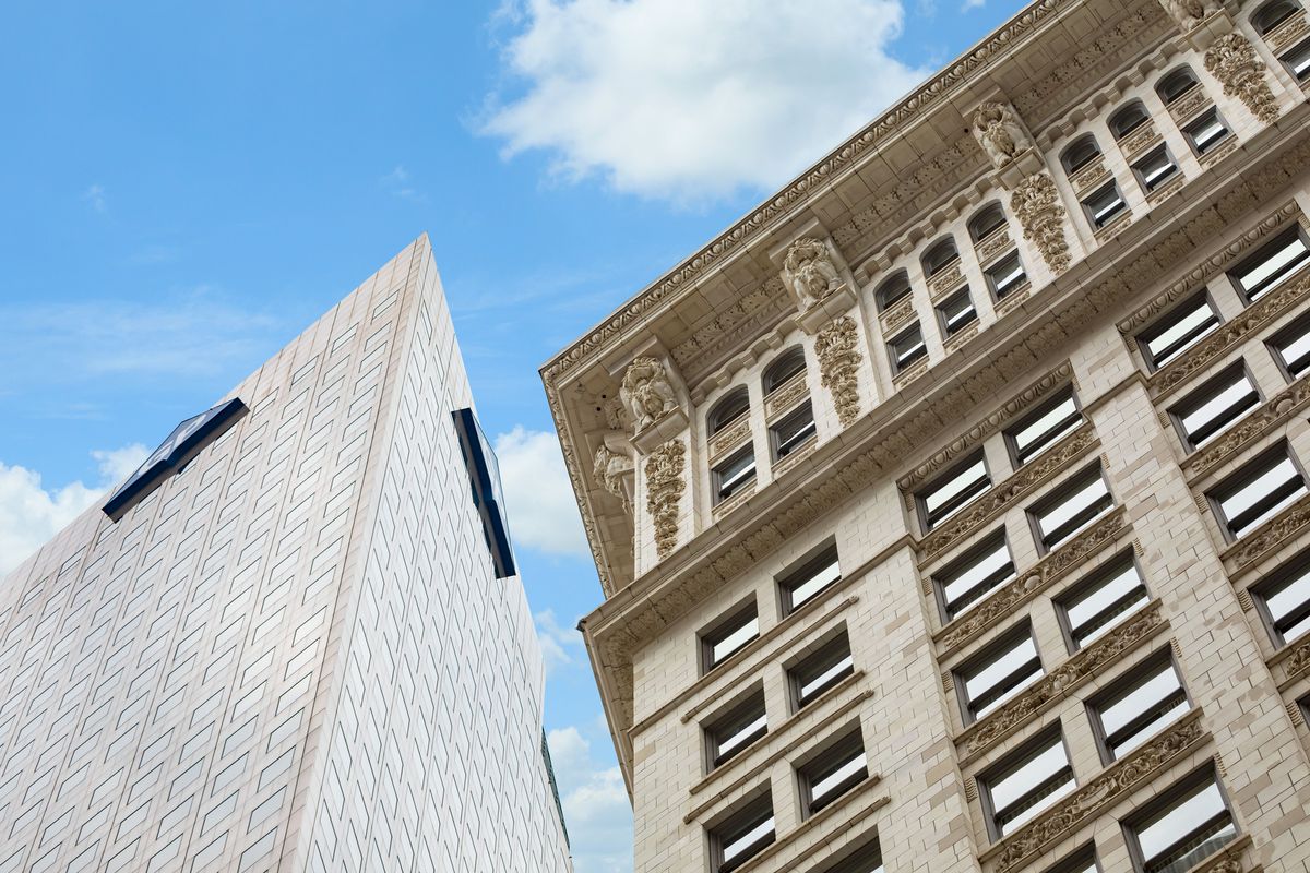 A modern building stands next to a classical one in downtown Atlanta, against a blue sky. 