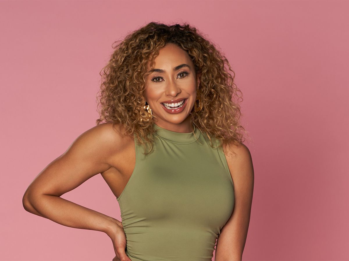 A Black woman with curly blonde hair, Raven Ross from season 3 of “Love Is Blind” on Netflix, is pictured on a pick background wearing a sleeveless, high-necked army green dress.