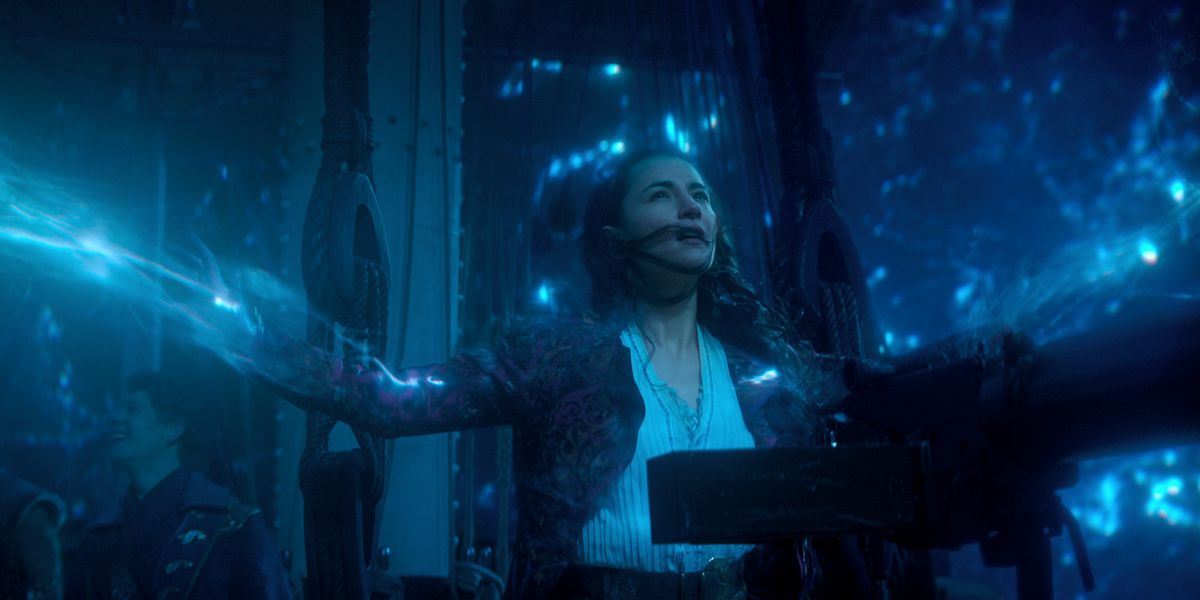 alina starkov with her arms outstretched, channeling glowing blue light