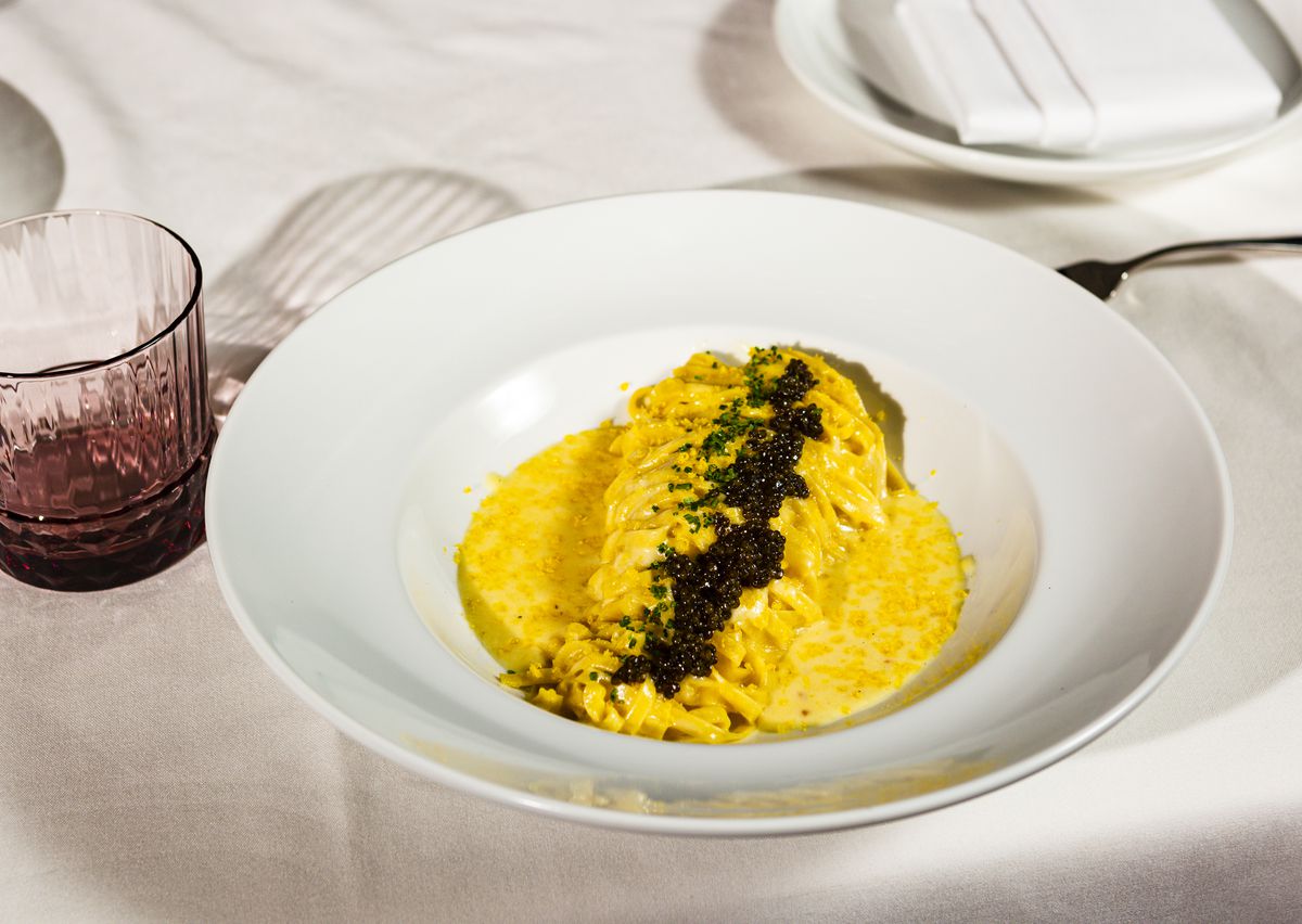 Fettuccini golden ossetra caviar on a white table.