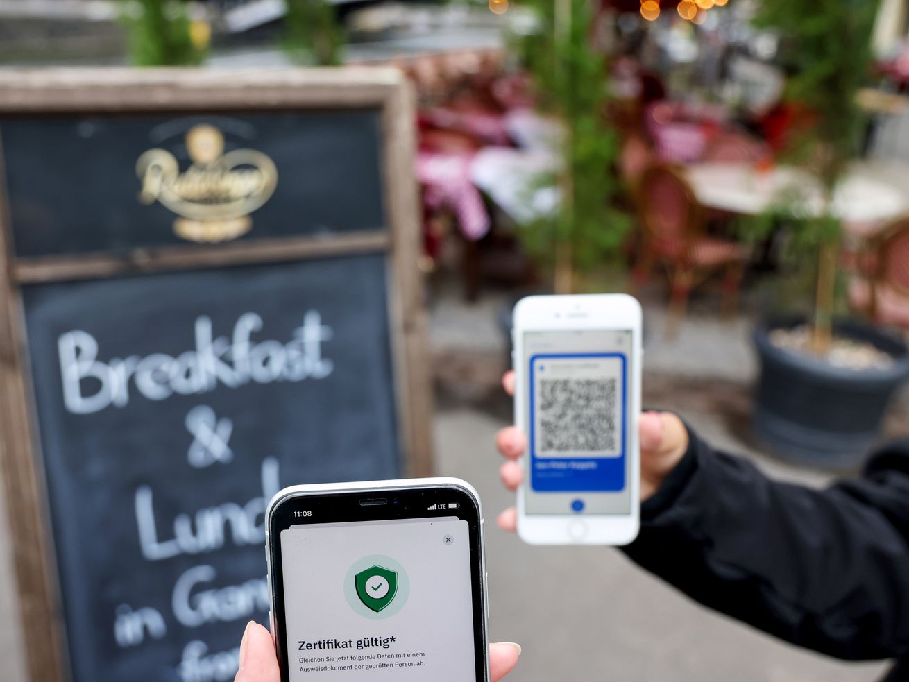 A restaurant patron holds up their phone with a QR code so the host can scan it with their phone.