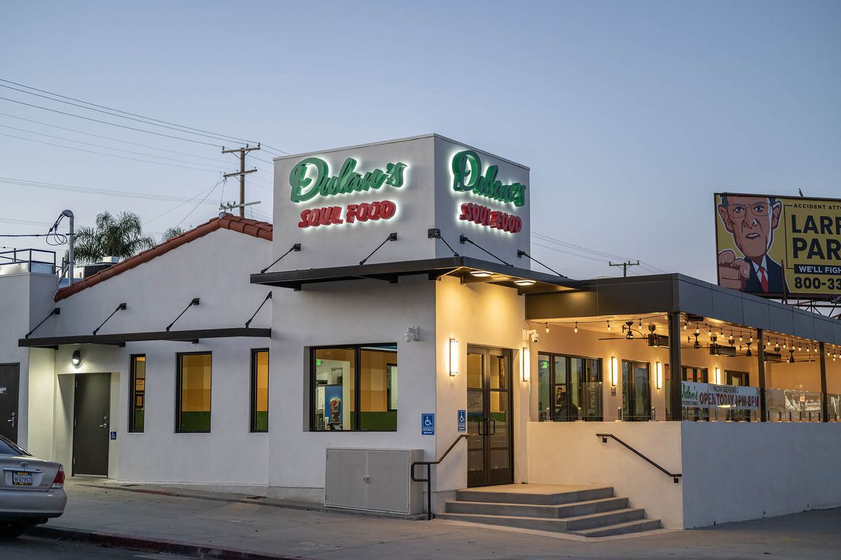 A corner view of a white painted restaurant building with green and red lettering at Dulan’s on Crenshaw in Los Angeles.