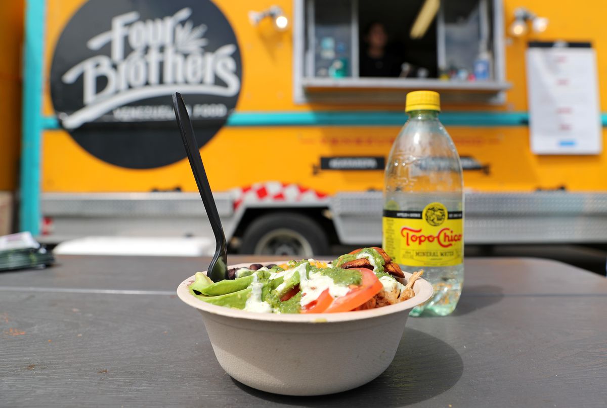 A bowl of food in front of a yellow truck with a sign reading 