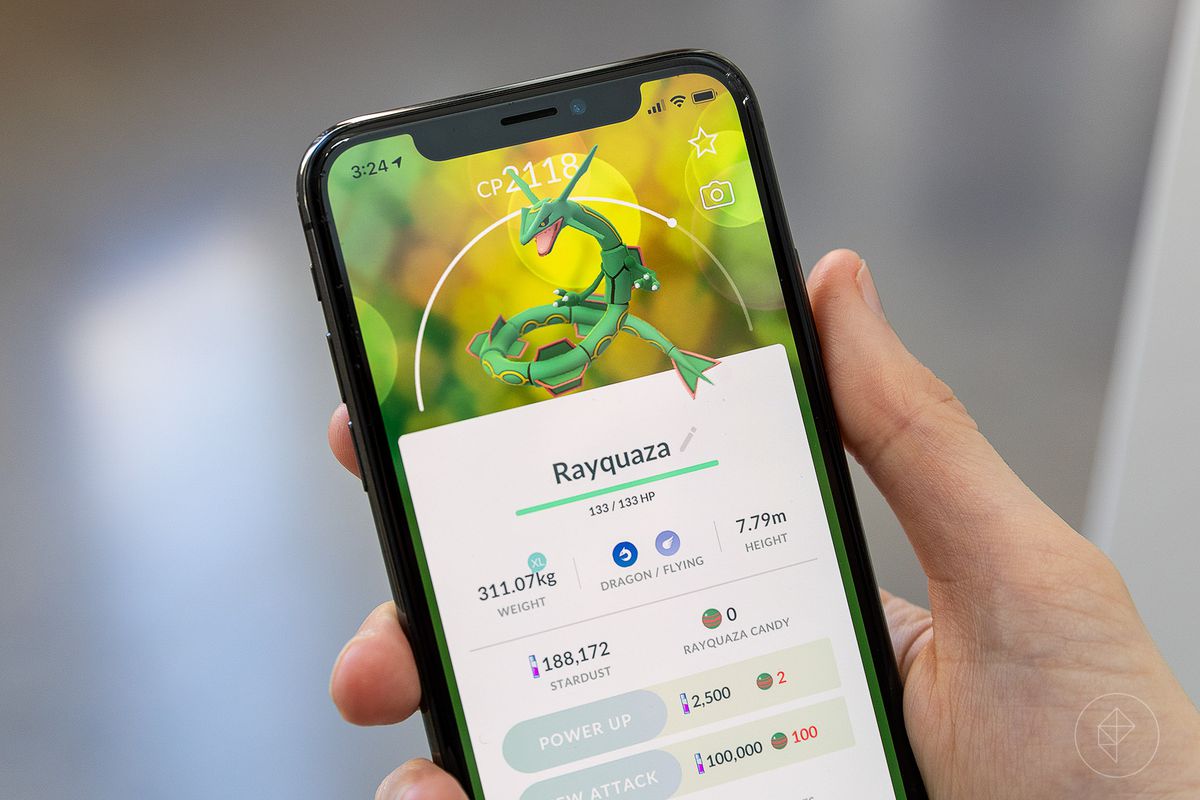A hand holds up an iPhone with Rayquaza’s Pokémon Go stat screen