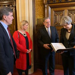 Elder Jeffrey R. Holland of the Quorum of the Twelve Apostles shows British Prime Minister Theresa May a bound copy of her family history records, including photographs of census and marriage records, as David Rutley, a member of Parliament, and Yvonne Kerr, wife of Stephen Kerr, a member of Parliament, look on at the Palace of Westminster on Wednesday, Nov. 21, 2018.