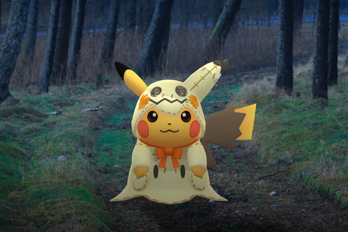A Pikachu wearing a Mimikyu costume stands in a spooky forest.
