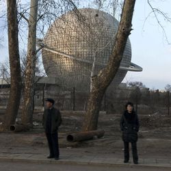 Seen through a moving car's window, a man and a woman stand in front of a planetarium at the Three Revolutions Exhibition Hall in Pyongyang, North Korea, Thursday, April 11, 2013. 