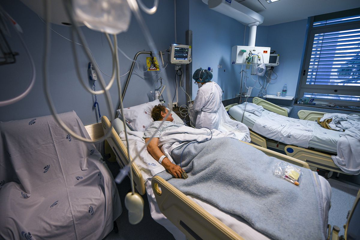 A person in a hospital bed, with tubes in the foreground.
