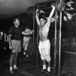1964-FSU football assistant coach Don James watching player lifting weights after practice in Tallahassee. 