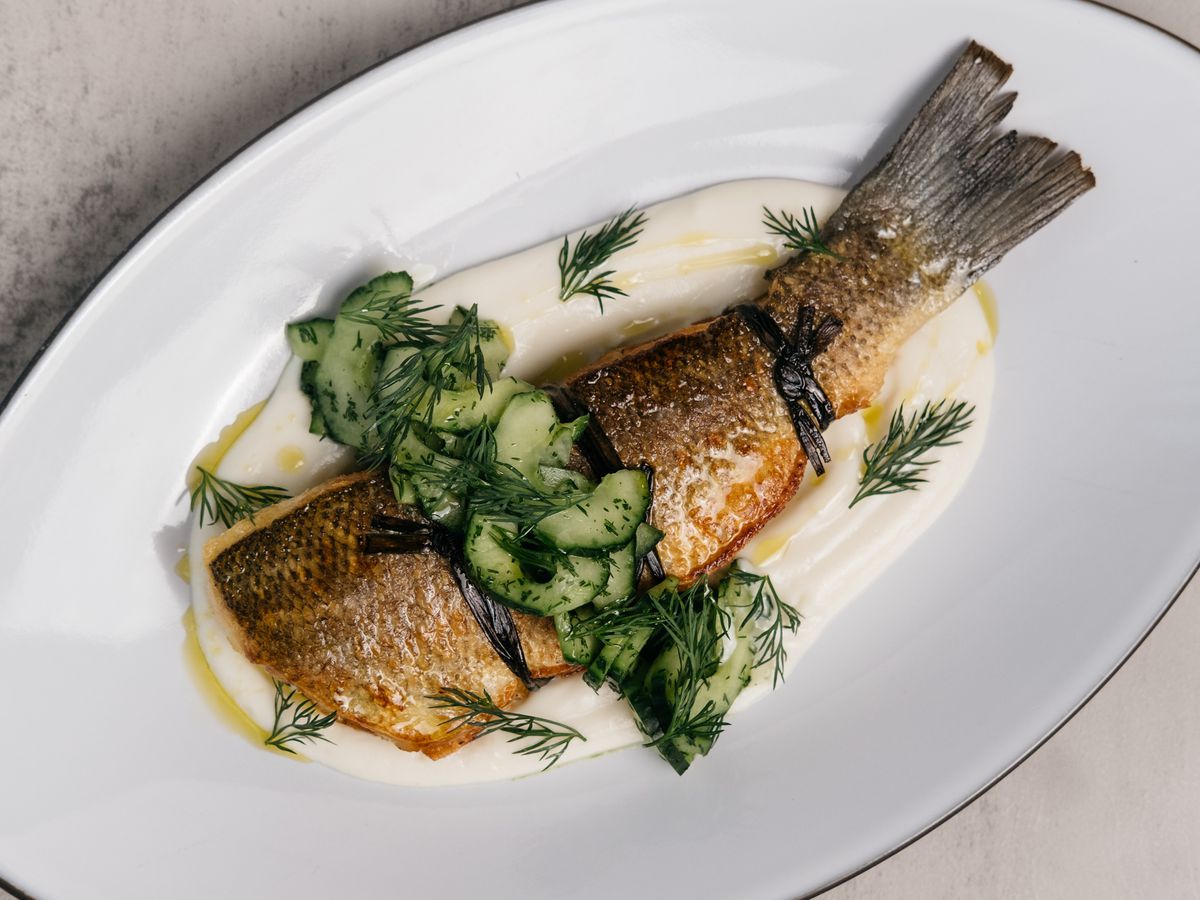 Branzino plated over a puree and topped with cucumber and dill.