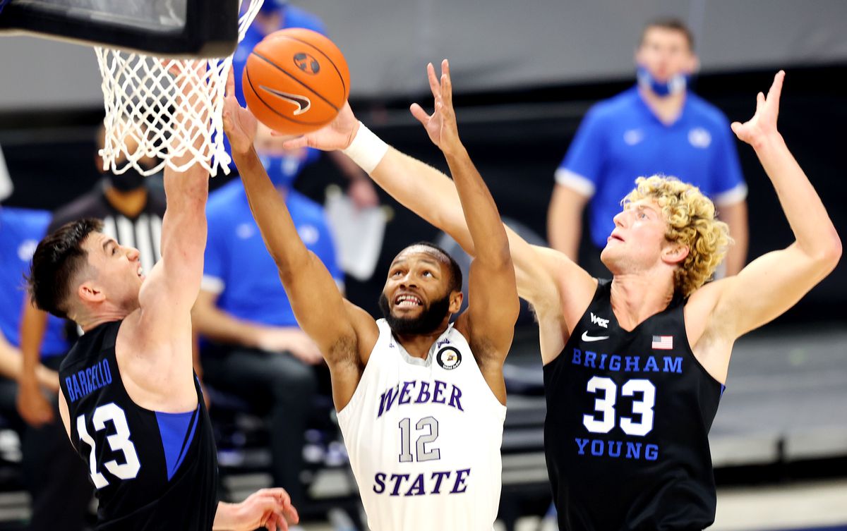 Brigham Young Cougars guard Alex Barcello (13) and Brigham Young Cougars forward Caleb Lohner (33) defend Weber State Wildcats guard Isiah Brown (12) as they play an NCAA basketball game at Vivint Smart Home Arena in Salt Lake City on Wednesday, Dec. 23, 2020.