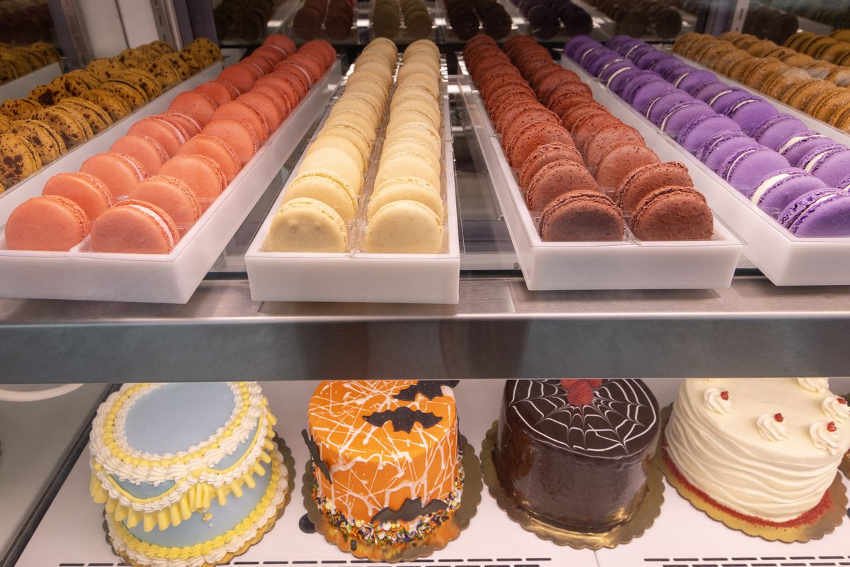 A close-up view of a pastry case filled with French macarons and decorated cakes.