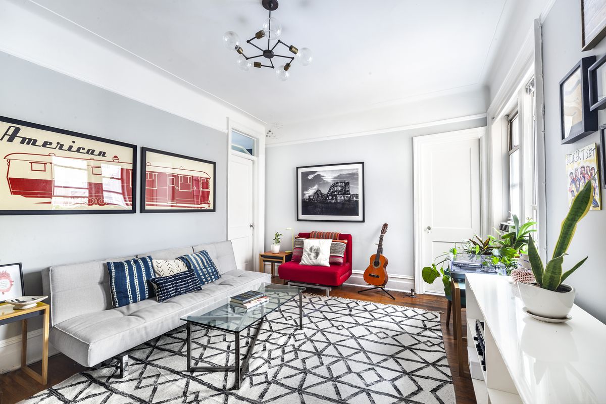 布鲁克林高地(Brooklyn Heights)一套公寓内的生活区，内有硬木地板、浅灰色沙发、玻璃咖啡桌、灰色墙壁和底座线材。