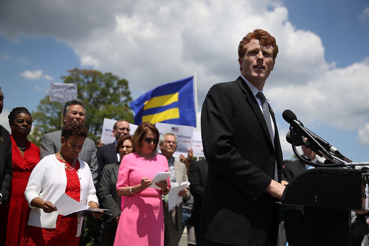 Joe Kennedy speaks at a podium in front of an equality flag.