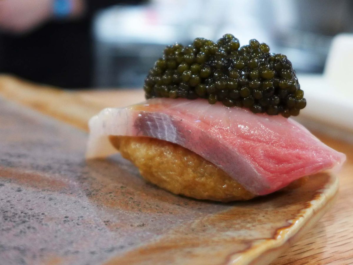 A piece of fish with black eggs on top.