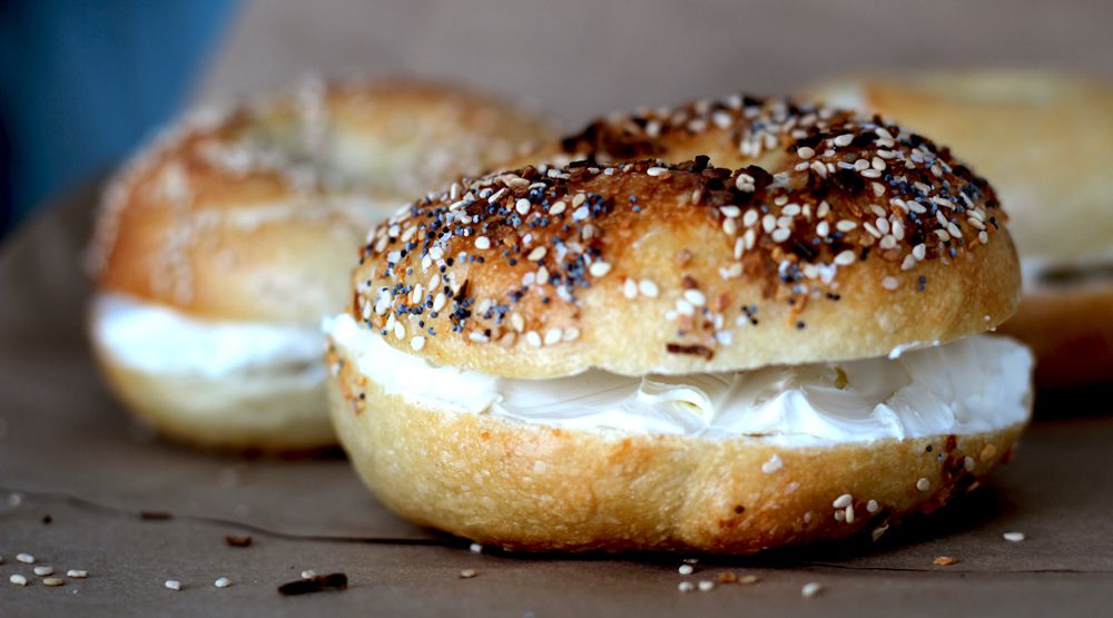 Crusty poppyseed topped bagel, sliced with a thick layer of cream cheese in the middle