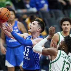 BYU guard Alex Barcello, left, shoots next to Oregon forward Quincy Guerrier during the second half of an NCAA college basketball game in Portland, Ore., Tuesday, Nov. 16, 2021.