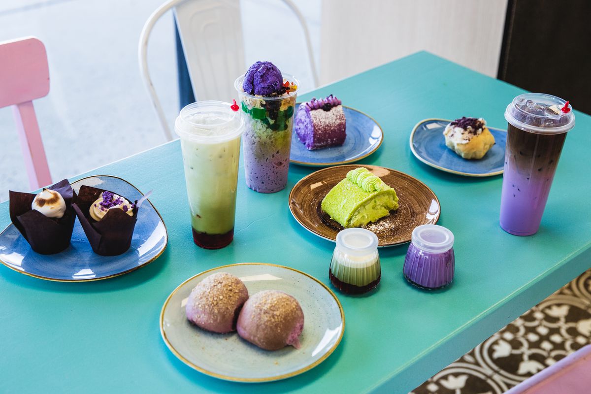 A table laid with plates of colorful desserts and tall cups of milk tea.