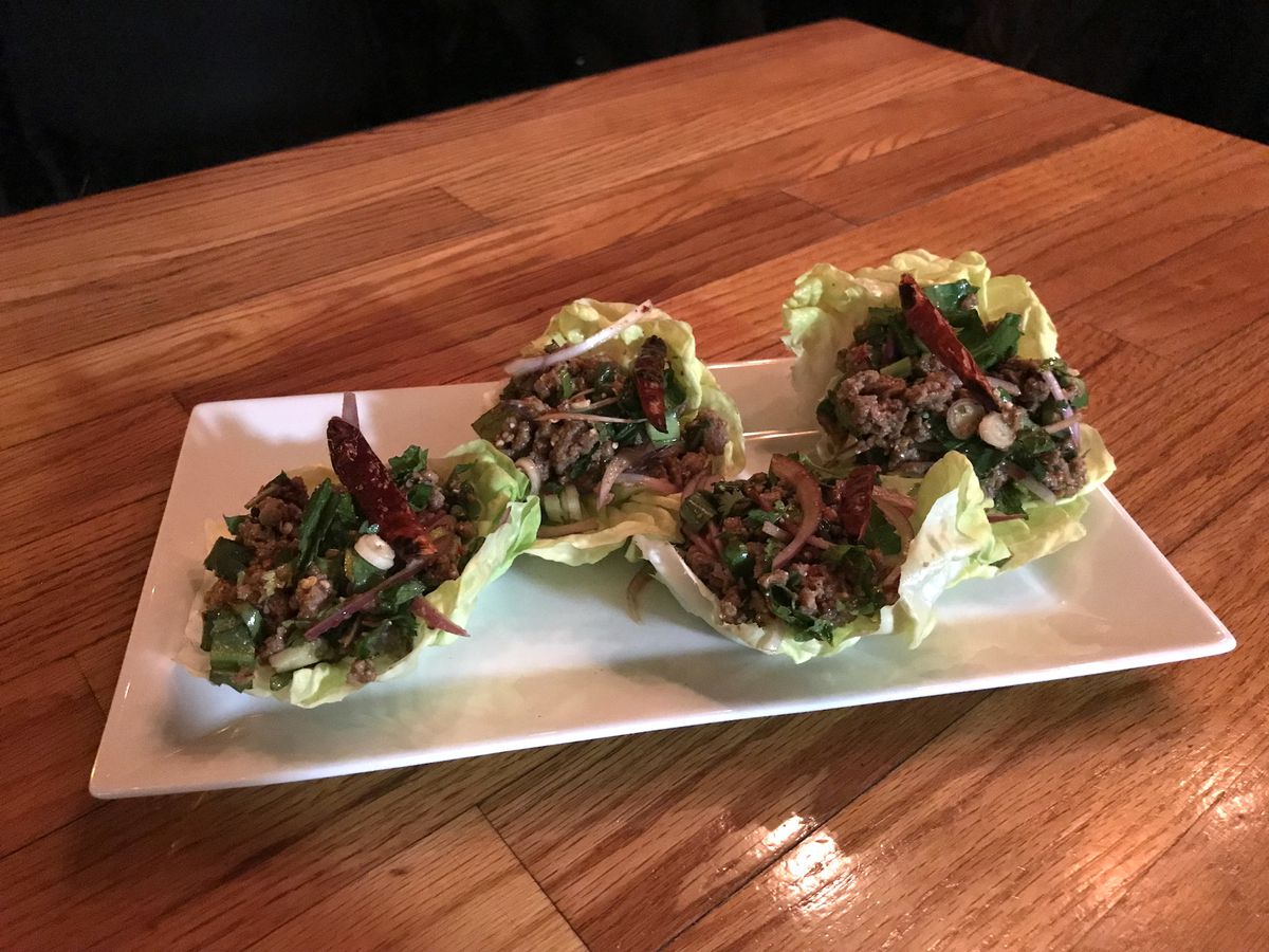 A white plate with four bibb lettuce cups filled with Impossible meat larb with chiles.