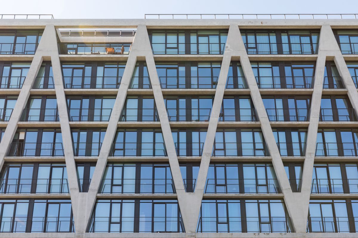 Exterior of high-rise with a grey, concrete, zig-zagging skeletal facade. 