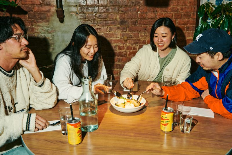 A group of four diners digs into a dessert with yellow cans surrounding them.