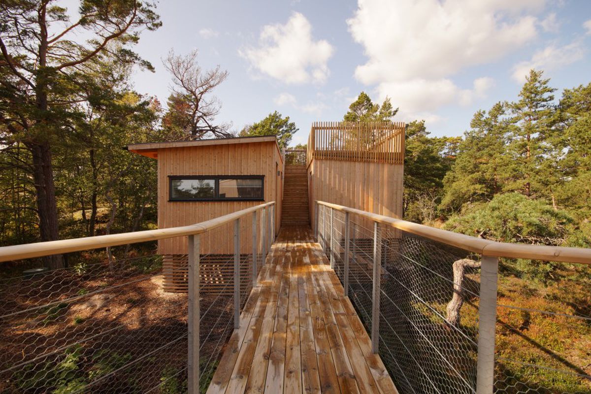 Small wooden house on deck that’s connected to a walkway.