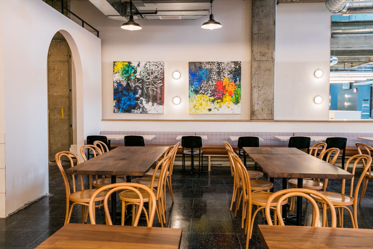 Communal are surrounded by white walls with rainbow colored paintings at Fort Street Galley.