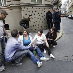 Injured people sit on a sidewalk after a explosion downtown Prague, Czech Republic, Monday, April 29, 2013. Police said a powerful explosion has damaged a building in the centre of the Czech capital and they believe some people are buried in the rubble. (AP Photo/Petr David Josek)