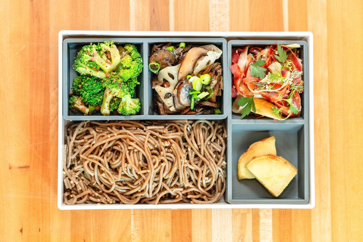 A bento box with noodles and vegetables.