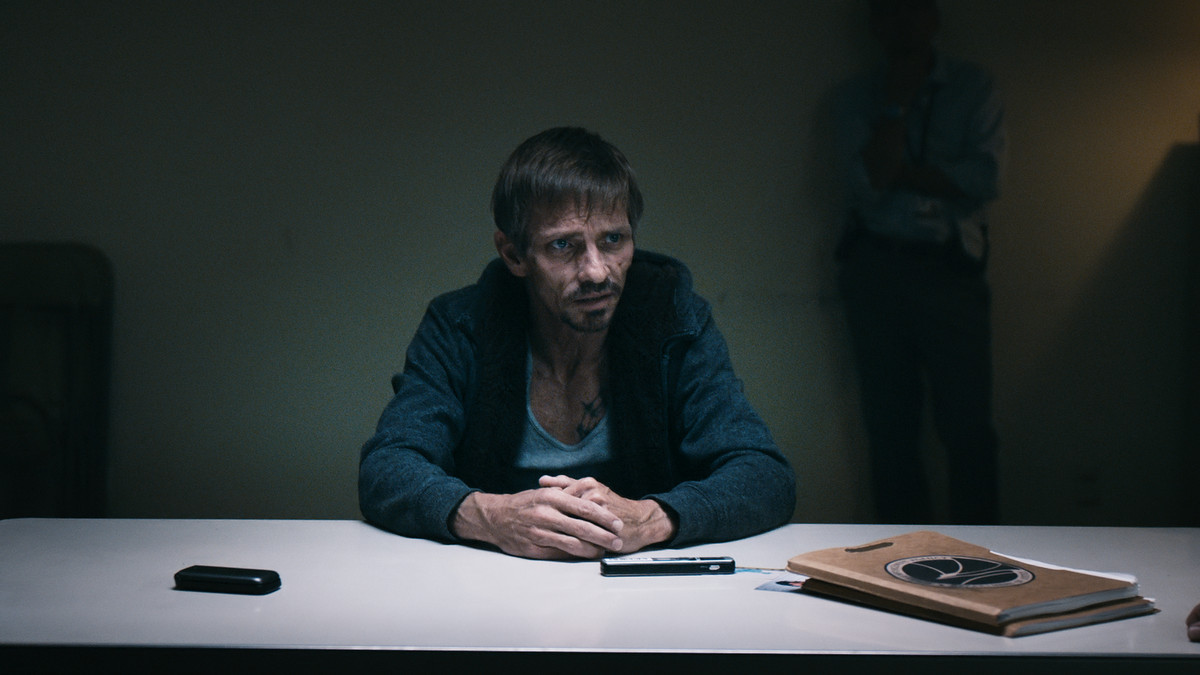 a scruffy man at the interrogation tanle