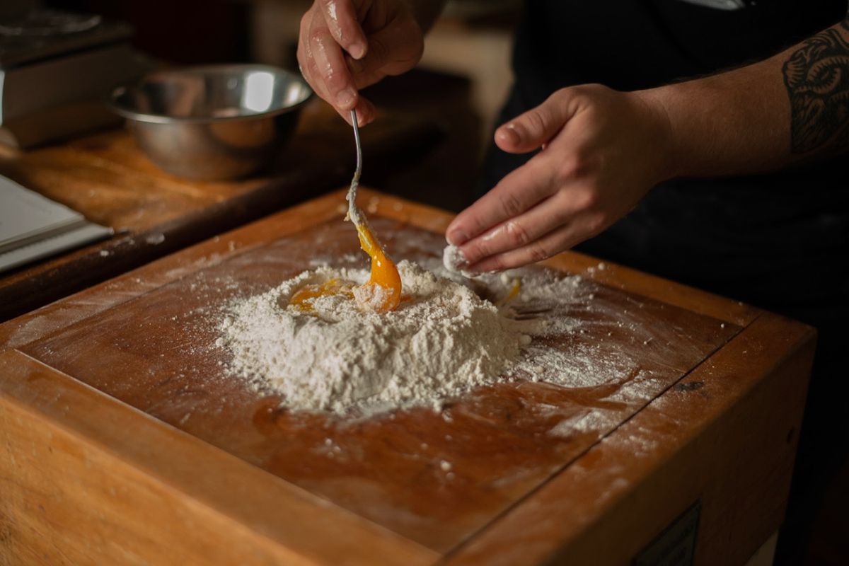 A chef mixing flour with egg yolk.