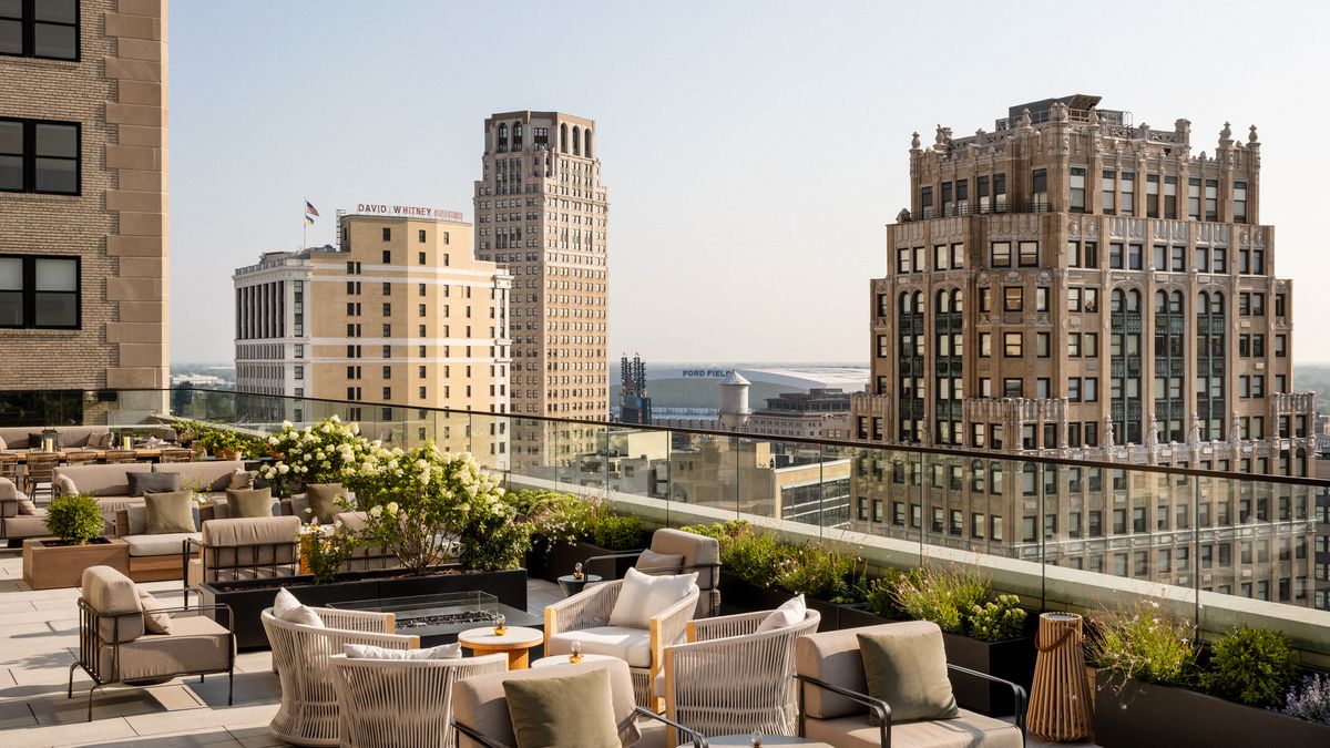 An outdoor rooftop patio with seating and foliage and views of downtown Detroit, Michigan.