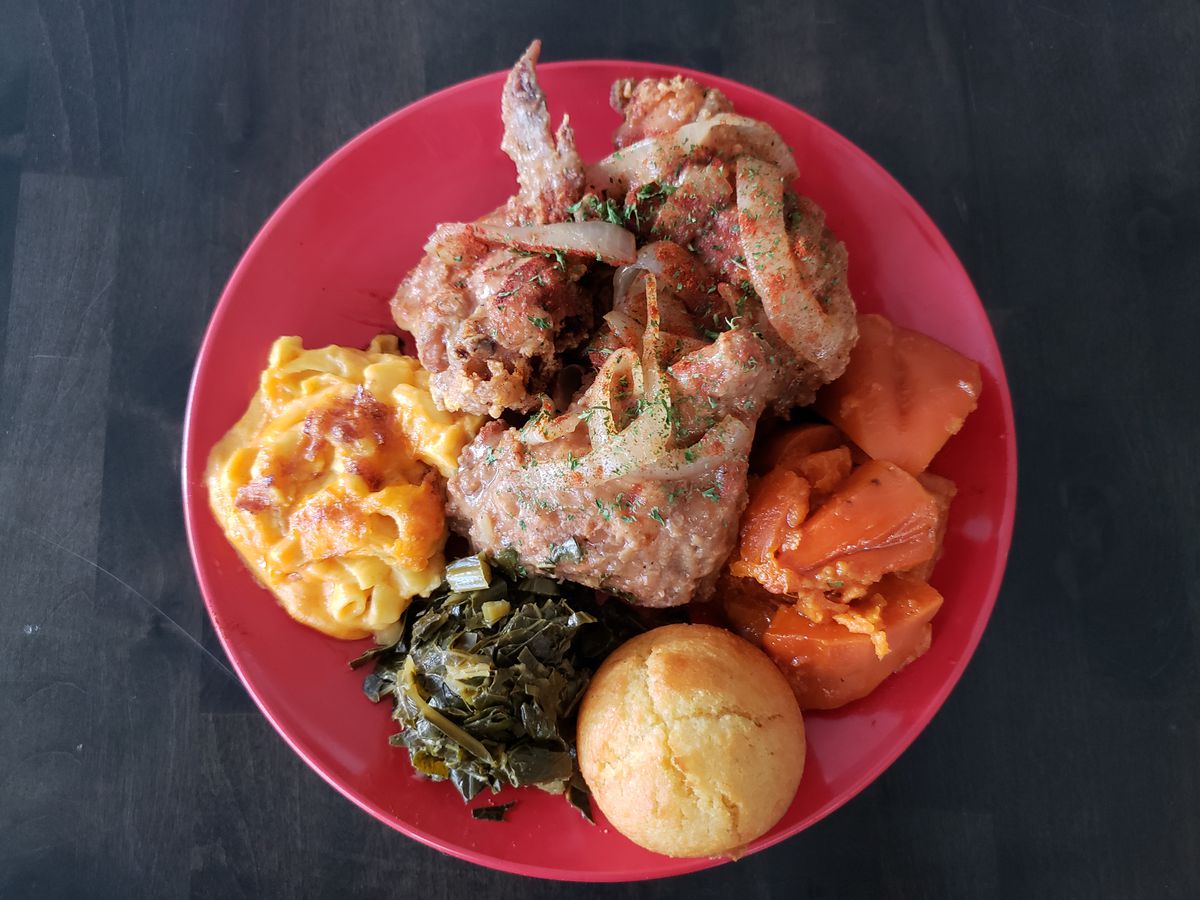 Smothered fried chicken with mac and cheese, greens, cornbread, and sweet potatoes at Dulan’s Soul Food in Inglewood, California.