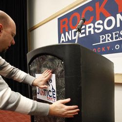 Cory Headley puts a Justice Party sign on the podium in preparation for Rocky Anderson's acceptance of the Justice Party nomination for president of the United States in Salt Lake City, Friday, Jan. 13, 2012.