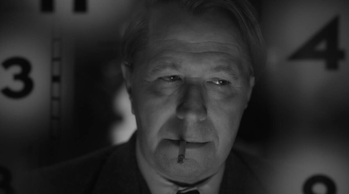 A black and white image of a man’s face, his nose bloodied, surrounded by surrealist clocks.