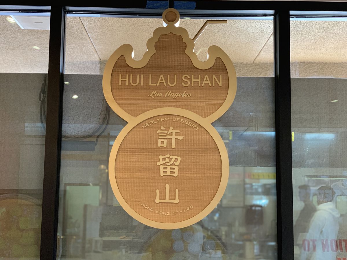 Wooden sign of Hui Lau Shan hanging from a glass window.