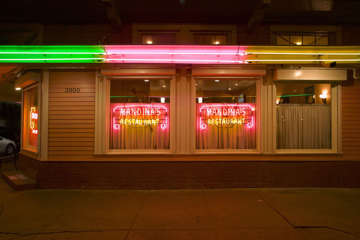 Mandina’s Restaurant with glowing neon window signs night exterior.