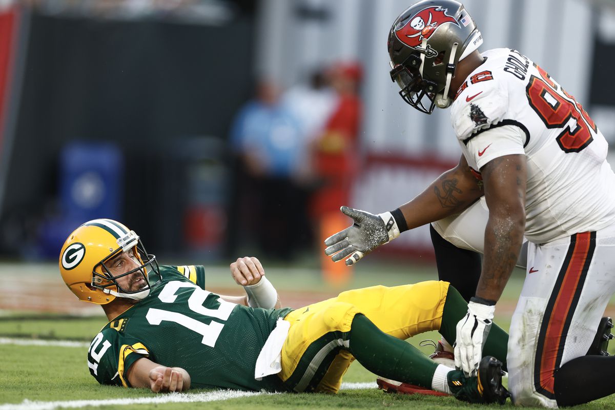 Aaron Rodgers of the Green Bay Packers is helped up off the field by William Gholston of the Tampa Bay Buccaneers during the fourth quarter at Raymond James Stadium on September 25, 2022 in Tampa, Florida.