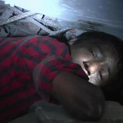 In this image taken from AP video, garment worker Mohammad Altab moans to rescuers for help while trapped between concrete slabs and next to two corpses in a garment factory that collapsed Wednesday in Savar, near Dhaka, Bangladesh, Thursday, April 25, 2013. Deep cracks visible in the walls of the Bangladesh garment building had compelled police to order it evacuated a day before it collapsed, officials said Thursday. More than 200 people were killed when the eight-story building splintered into a pile of concrete because factories based there ignored the order and kept more than 2,000 people working. 