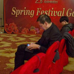 A woman takes a photo of attendees at a press conference for the China Central Television's annual hours-long Spring Festival Gala held in Beijing, Monday, Feb. 2, 2015. China’s state broadcaster is attempting to extend the international reach of its annual Chinese New Year variety show by making rights available to foreign broadcasters and putting related content on Twitter and other social network sites. 