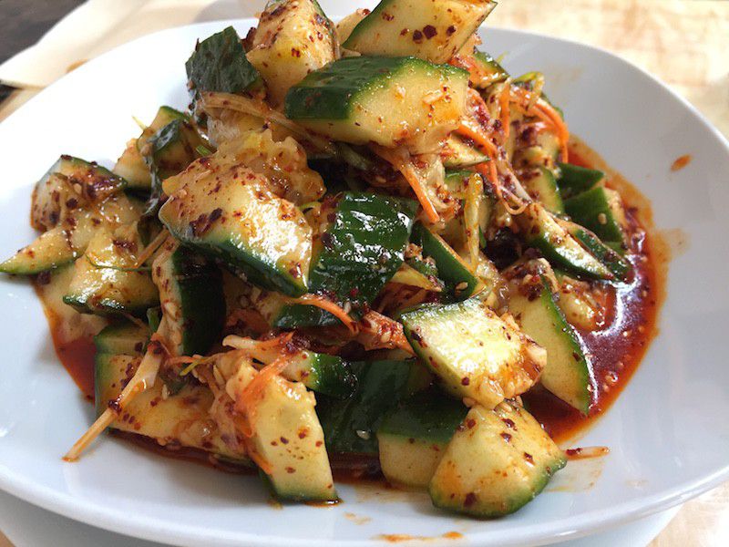 A plate piled high with sliced cucumbers in red sauce