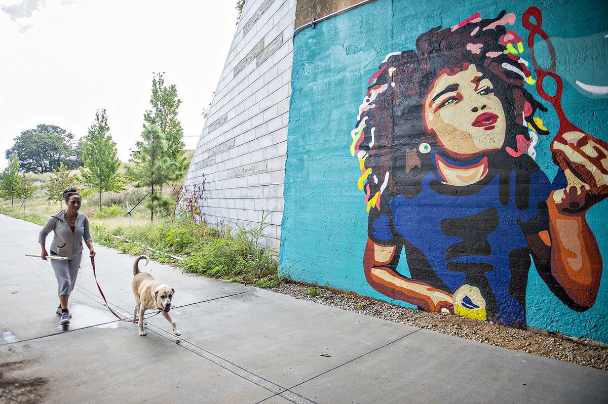 A mural with a lady walking a dog beside it. 