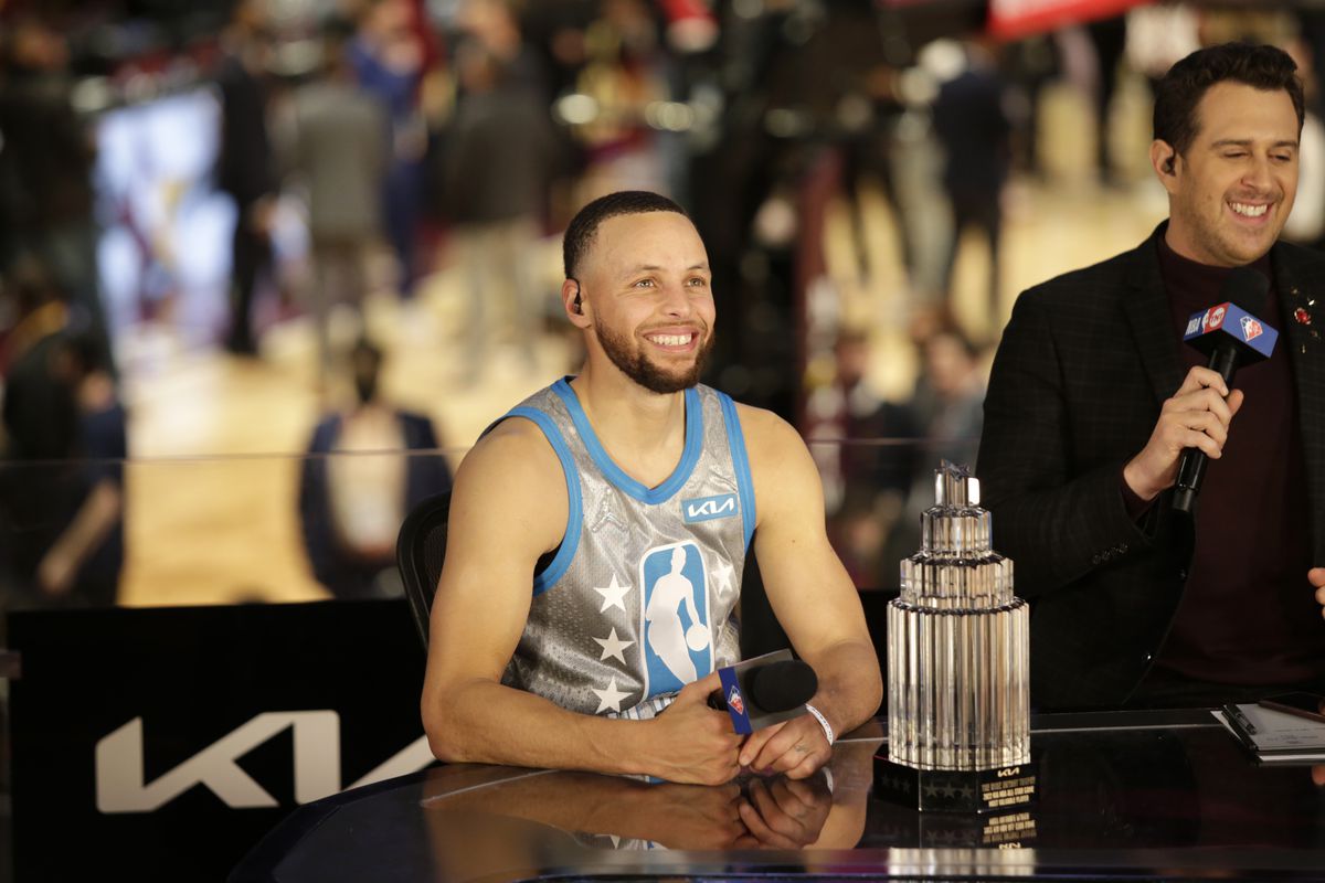 Steph Curry smiling with an All-Star MVP trophy.